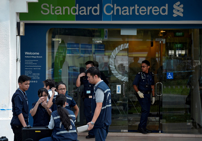 Police officers work at scene of a robbery at Standard Chartered Bank branch in Holland Village, Singapore. — Reuters photo