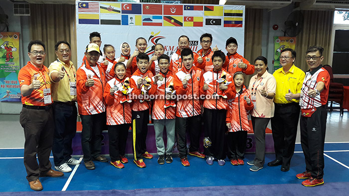 The Sarawak wushu team celebrating with chef-de-mission Datuk Abdul Karim Hamzah (third left), his wife Datin Zuraini Abdul Jabbar (third right), Batu Kitang assemblyman Lo Khere Chiang (second right), Wushu Federation of Sarawak president Allen Wong (right), deputy president James Ting (second left) and Roger Chan (left) after the first day of wushu competition at SJK Chung Hua No. 3 Alumni Hall yesterday.