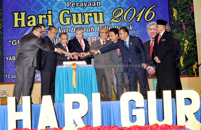 Ahmad Zahid (centre) cuts the cake during the Hilir Perak district level Teachers’ Day 2016 celebration. Joining him are Rozi Puteh Ismai (fourth left) and other Perak exco. — Bernama photo