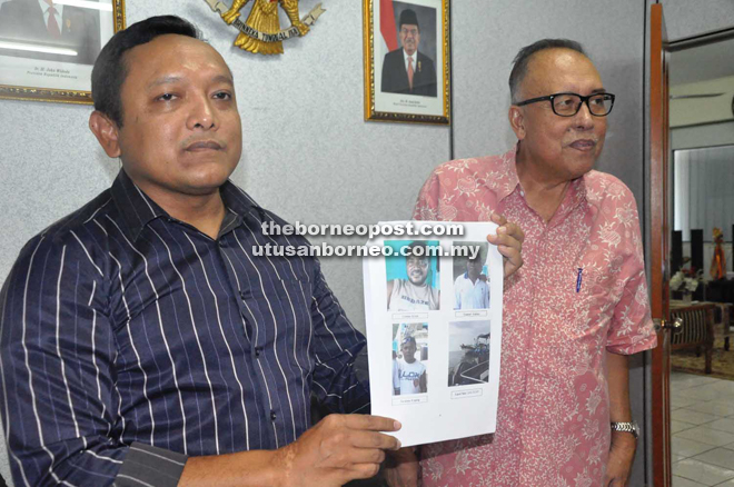 Police personnel Nafi Armand at the Consulate of Indonesia, Tawau, showing picture of the three abducted Indonesians while Fatah (right) looks on.