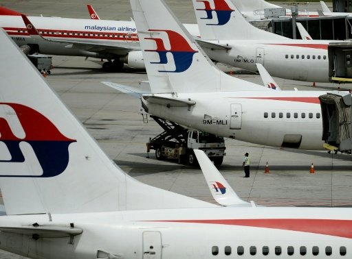 Malaysia Airlines ground staff walk past Malaysia Airlines aircraft parked on the tarmac at the Kuala Lumpur International Airport in Sepang. - AFP Photo