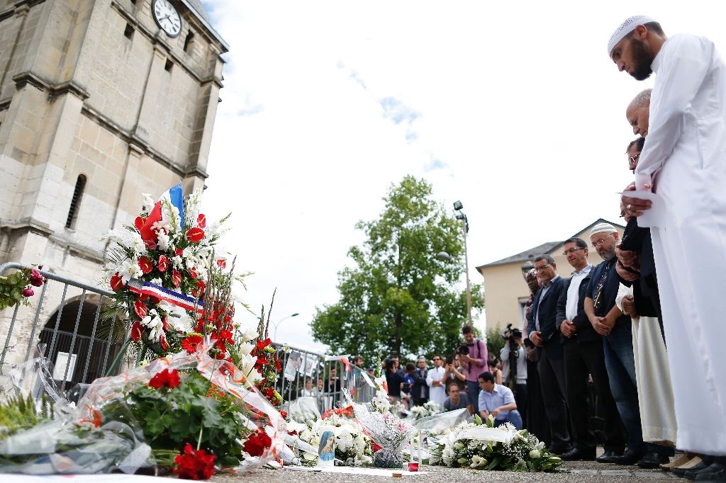 Muslims put flowers and hold a minute of silence in front of the church in Saint-Etienne-du-Rouvray, western France, where French priest Jacques Hamel was killed. Photo by AFP