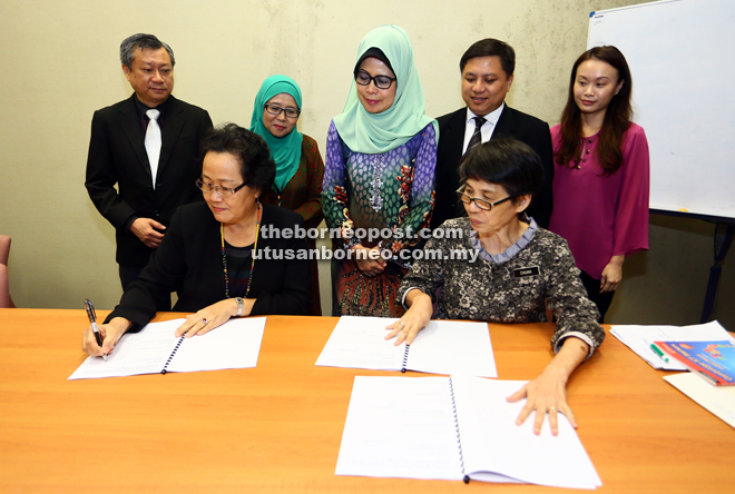 Fatimah (standing, centre) witnessing the signing of the MoA by the ministry’s permanent secretary Megir Gumbek (seated left) and Chuah (seated right). - Photo by Muhd Rais Sanusi