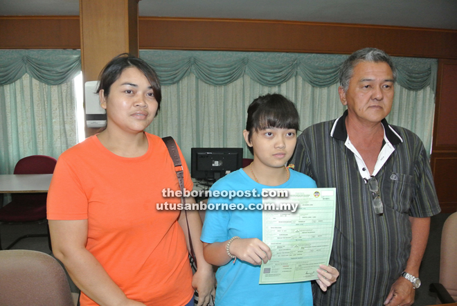 Angelina, holding her non-citizen birth certificate with her parents. 