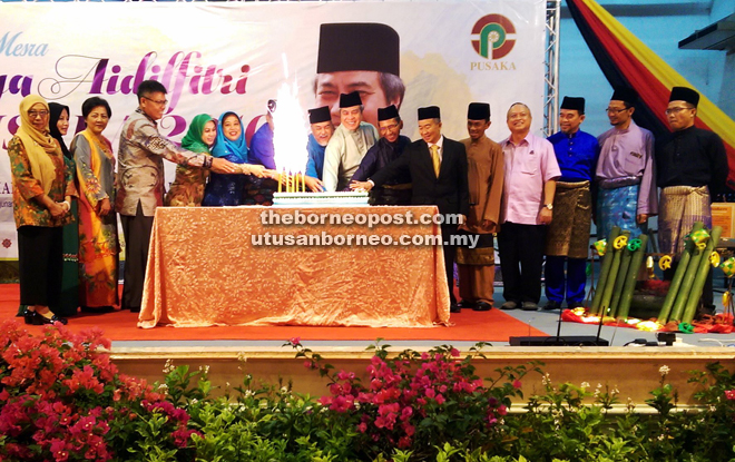 Awang Tengah (eighth right), flanked by Asfia (on his right) and Sarudu, together with Naroden (sixth right) and other guests cut the Hari Raya cake during the open house.