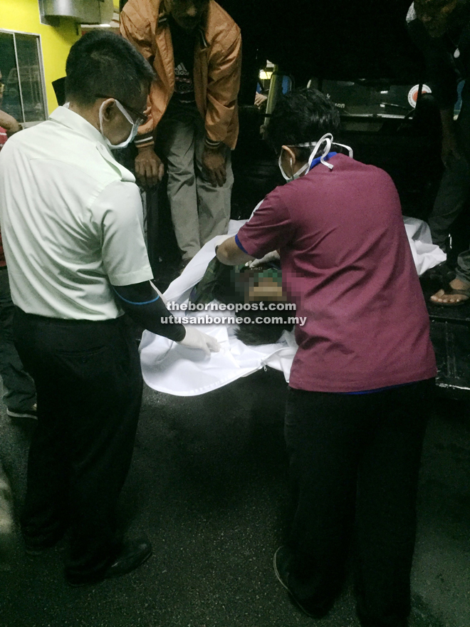 Doctors inspecting the body of seven-year-old Adam Hadiman after it was brought by police to the Sarawak General Hospital late Tuesday night.