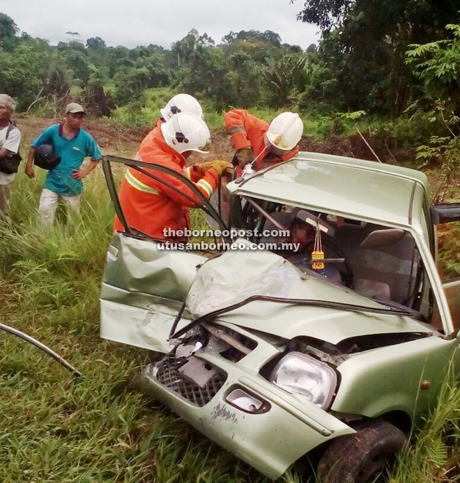 Firemen working to rescue the trapped driver.