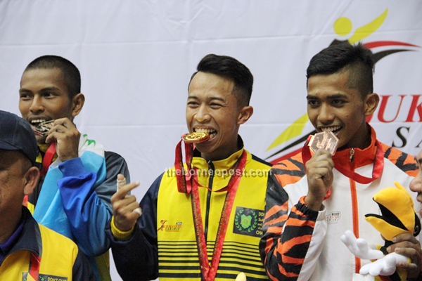 Muhammad Aizat (centre), Mohamad Harith and Syazwan (right) seen biting their medals when posing for press photographers after the presentation ceremony. 