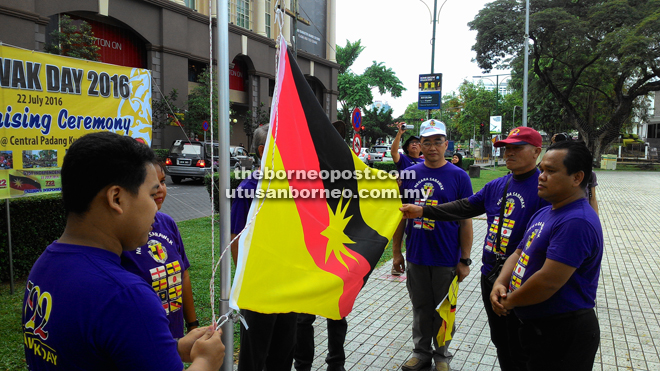 Ng (third right) and others stand at attention during the flag-raising ceremony.