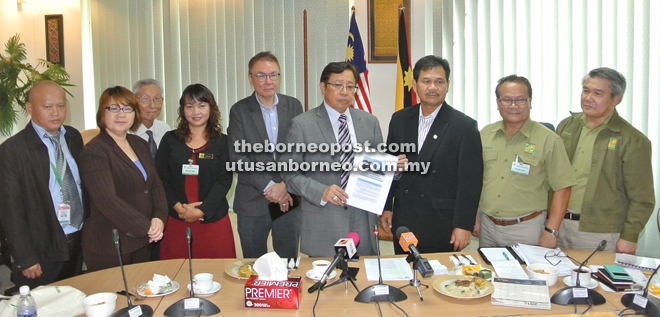 Abang Johari holds up a document on Bako National Park after the news conference. On his left is Ministry of Tourism, Arts and Culture permanent secretary Datu Ik Pahon Joyik. — Photo by Hiew Man Chien