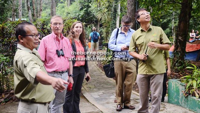 Lovejoy (second left) is briefed by Oswald (left) during a tour around Semenggoh Wildlife Centre.