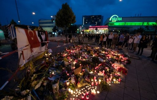 Candles and flowers lie in front of the Olympia-Einkaufszentrum shopping centre in Munich. Photo by AFP