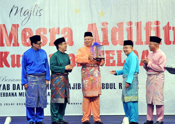 Najib receiving a gift at the Hari Raya open house of the Felda Group at Felda Towers. Also present are Deputy Minister in the Prime Minister’s Department Datuk Razali Ibrahim (second left) and Felda chairman Tan Sri Mohd Isa Abdul Samad (second right). — Bernama photo