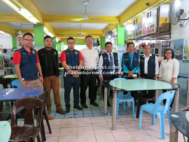Talie (fourth right) in a coffee shop with other enforcement officers. He is flanked by SDC public health supervisor Wong Sie Mee (left) and Abang Abdul Razak.