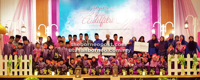 Zamani (standing, 15th left) presents a total of RM143,890.87 business tithe at the open house yesterday
