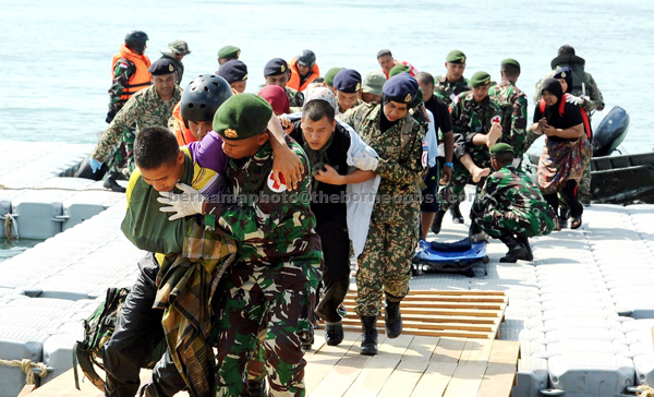 Malaysian Armed Forces personnel and their Indonesian counterparts carrying 51 ‘flood victims’ to a safer place during the joint exercise. — Bernama photo 