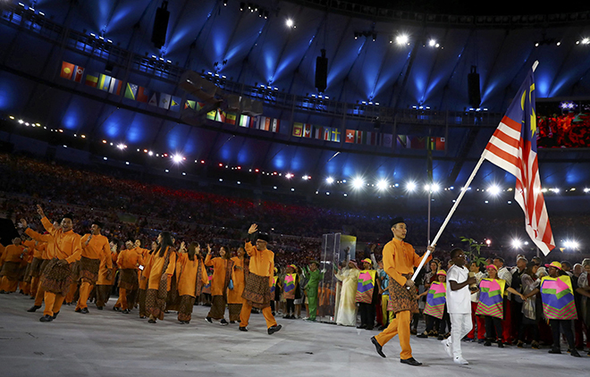 Flagbearer Datuk Lee Chong Wei leads the Malaysian contingent into the stadium. (Inset) Fireworks explode during the curtain-raiser. — Reuters photo