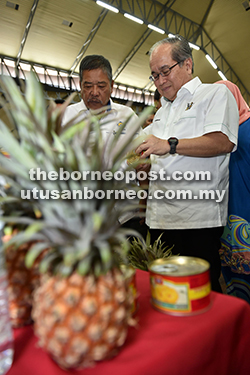 TERTARIK: Uggah diiringi Sahdan melihat produk nanas yang dipamerkan sempena Pelancaran Program Banci Tanaman Nanas di Sarawak 2016 di Dewan Suarah Samarahan, semalam. 