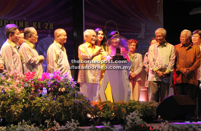 Taib touches the globe to mark the 28th anniversary of Kuching City and Kuching Festival, while (from left) Dr Sim, Uggah, Chan, Raghad, Abang Wahap and Manyin look on. — Photo by Chimon Upon