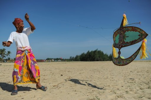Kitemaker Shafie Jusoh launches a traditional 'wau bulan' kite at Pantai Geting Beach, on the outskirts of Tumpat, peninsular Malaysia's north-eastern Kelantan state. Photo by AFP
