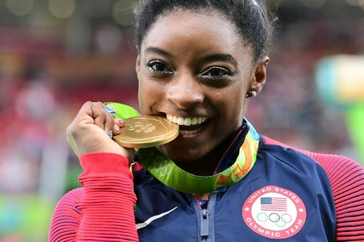 US gymnast Simone Biles celebrates with her gold medal after the women's individual all-around final of the Artistic Gymnastics during the Rio 2016 Olympic Games. Photo by AFP