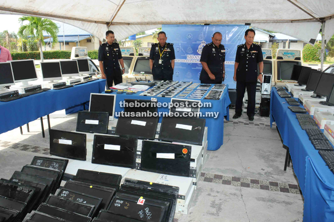 Salehhudin (second right), Jauteh (right) and other police officers with the slot machines, computers and tablets that were seized during the seven-month operations.