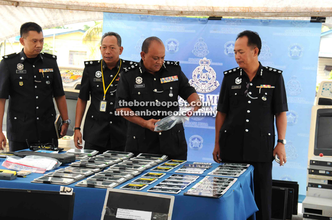 Salehhudin (second right) inspecting some of the computer tablets that were seized in the operation as Jauteh (right) and other police officers look on.