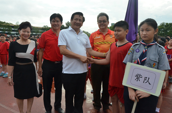 Wong (third left) shaking hands with a pupil of Chung Hua Primary School No.3 before Sports Day kicks off.