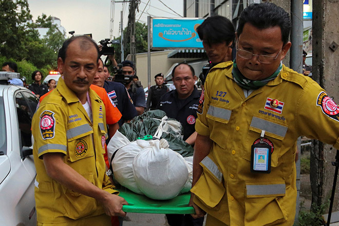 Rescue workers carry an unidentified body after a raid of a passport forgery gang in Bangkok. — Reuters photo