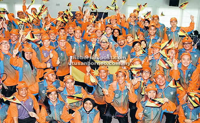 SEMANGAT WAJA: Fatimah dan Abdul Rahman (berdiri tengah) bergambar beramai-ramai bersama atlet dan pegawai kontinjen Sarawak selepas majlis penyerahan bendera di APMM semalam. — Gambar Chimon Upon