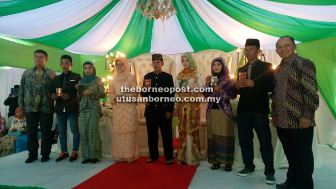 Fatimah (fourth left) in a group photo with Herman (right) and Jahar (left) after they presented marriage certificates to three couples in a symbolic ceremony.