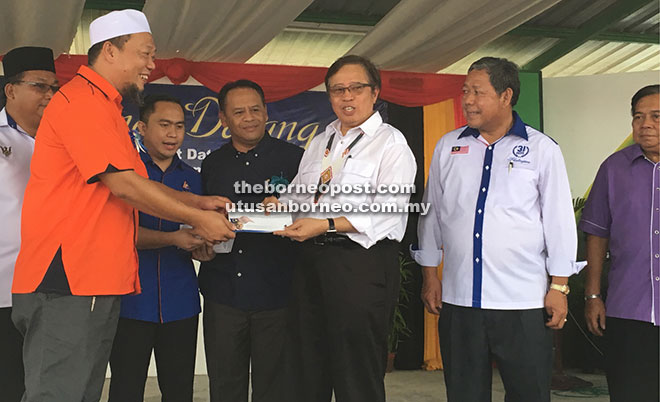 Abang Johari (second right) presents a flood relief aid to a Buso local. Looking on from right are Nogeh and Henry.