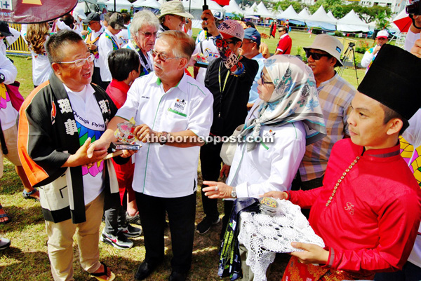 Sikie (second left) presents a souvenir to one of the international kite flyers. 