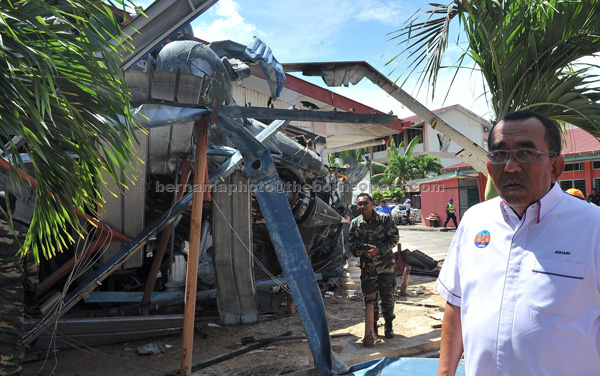 TINJAU KEADAAN: Johari (kanan) semalam melihat keadaan helikopter Nuri milik TUDM yang melakukan pendaratan cemas di SMK Balung Tawau di Tawau, kelmarin. Lapan pelajar sekolah dan seorang pekerja pembersihan cedera dalam insiden tersebut. — Gambar Bernama