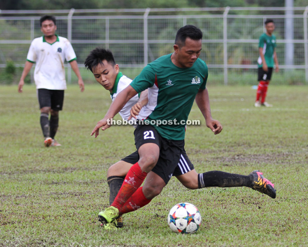 DIASAK: Penyerang DBKU, Azmie Kifli (jersi hijau) diasak pertahanan Petra Giant pada perlawanan Liga Kuching LSC di Padang D, Kuching Ahad lalu.