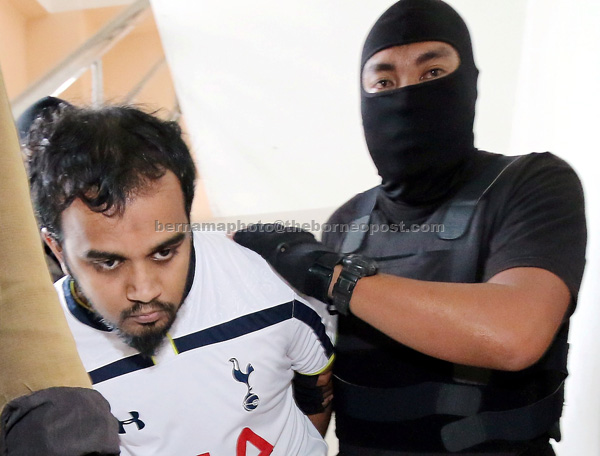 A policeman escorts Firdaus to the magistrate’s court. — Bernama photo