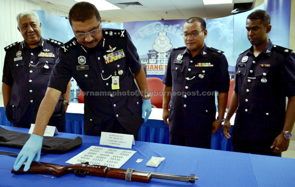 Ramli (second left) checking the air rifle that was seized in a raid at a flat at Bukit Beruang in Melaka. — Bernama photo