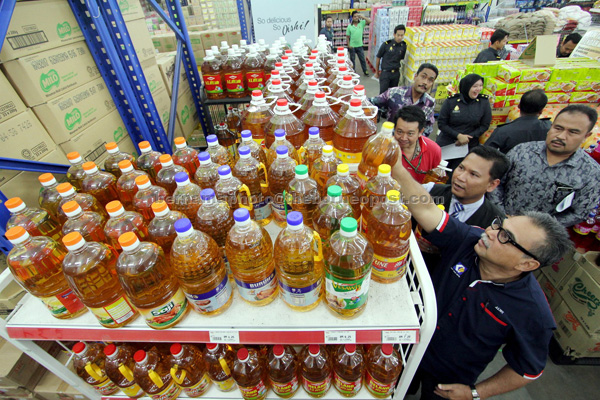 PERIKSA: Alwi (depan) bersama pegawainya memeriksa bekalan minyak masak di pasar raya TMG Mart Sdn. Bhd di Pahang semalam. — Gambar Bernama