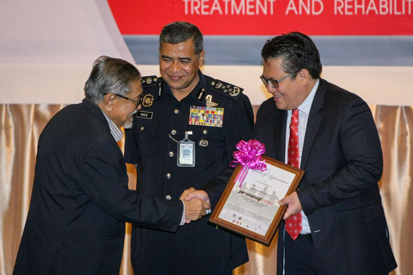 Nur Jazlan (right) presenting certificate of appreciation to former director of Criminal Investigation Department of Bukit Aman, Tan Sri Zaman Khan Rahim Khan (left) at the opening of an International Seminar on the Prevention of Drug Smuggling (PREVENT) 2016 at the Royal Malaysia Police College in Kuala Lumpur, while Khalid looks on. — Bernama photo