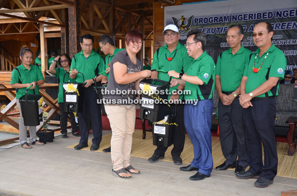 A representative of the composting pilot project receives Bokashi composting kit from Dr Sim (third right), while Gerawat (right),  Penguang (second right), Yii and others look on.