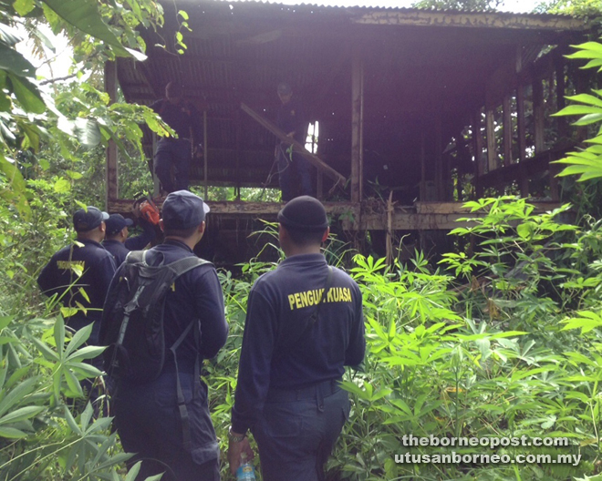 Land and Survey Department enforcement officers about to demolish one of the squatter houses.