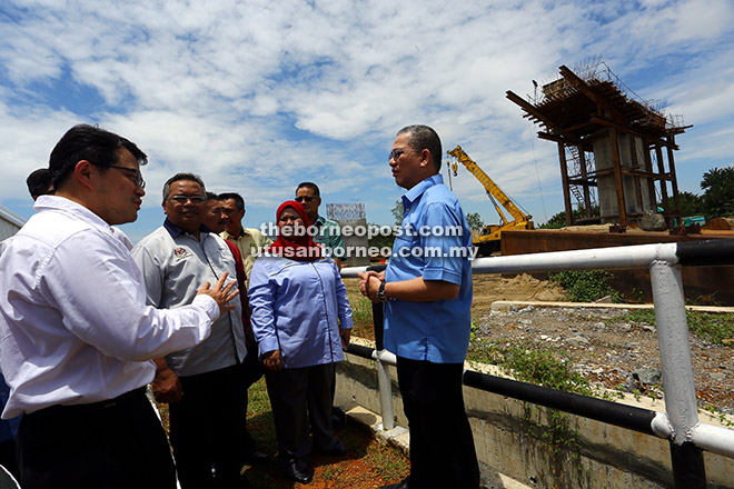 TAKLIMAT: Fadillah (kanan) mendengar penjelasan daripada pihak berkaitan semasa mengadakan lawatan ke tapak pembinaan Jambatan Batang Samarahan, semalam. Turut kelihatan Ahli Parlimen Kota Samarahan Rubiah Wang (dua kanan) serta yang lain.