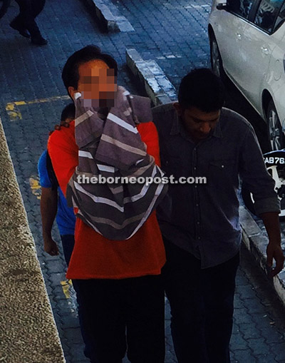 The suspect being led to the courthouse by an MACC officer in Kota Kinabalu, yesterday.