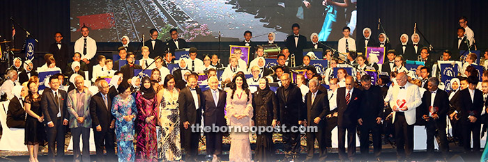 Guests-of-honour and special guests pose with performers (in the background). — Photo by Muhammad Rais Sanusi