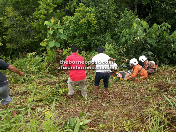 Firemen and members of the public bring up the victim from the ravine to the waiting ambulance.