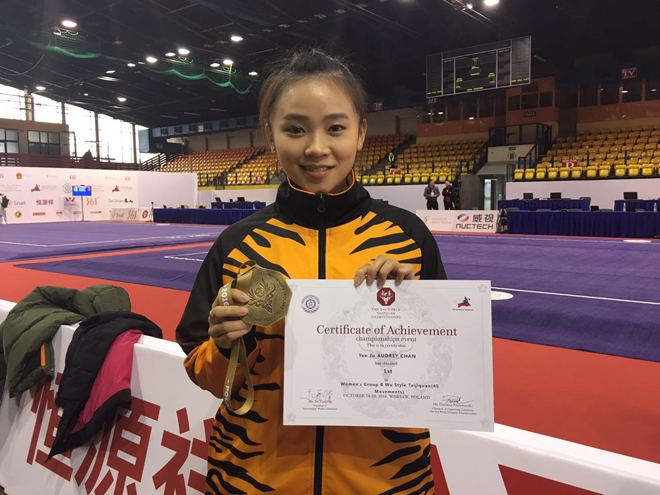 Audrey poses with her gold medal and certificate of achievement.