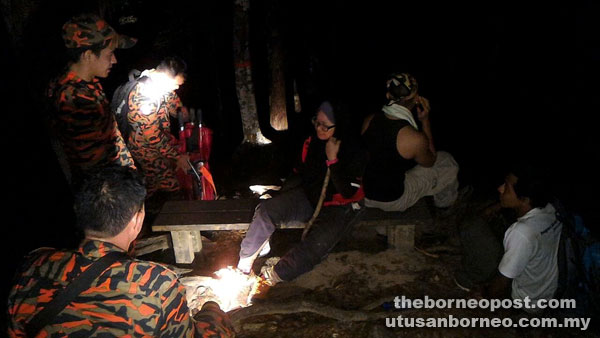 Rescue personnel speaking with the hiker who sustained an injury to her leg.