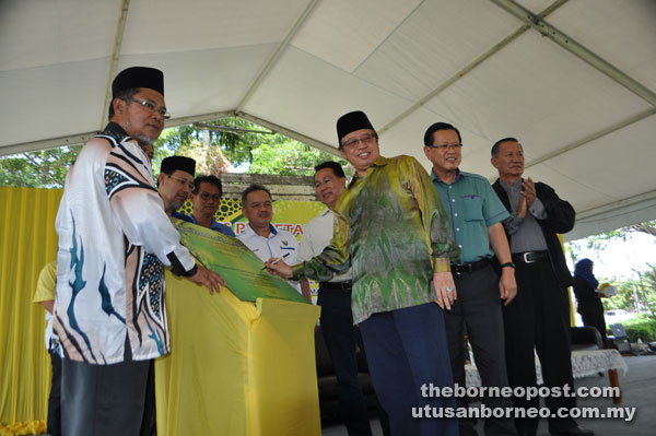 Abang Johari signs a plaque to mark the laying of the foundation stone for Surau Abu Bakar As Siddiq project at Desa Senadin. At second right is Lee while Abang Mohamad is at far left.