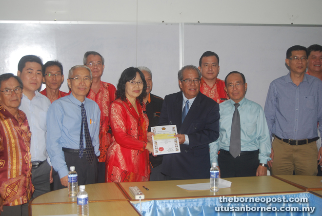 Ling (left) receives the award from Putit. Looking on are MHA members and teachers.