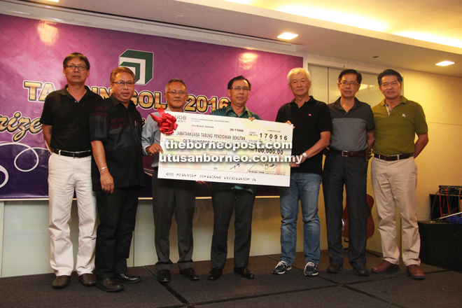 Meikle (left) receives a mock cheque from Wong while  Dr Rundi (centre) and others look on.